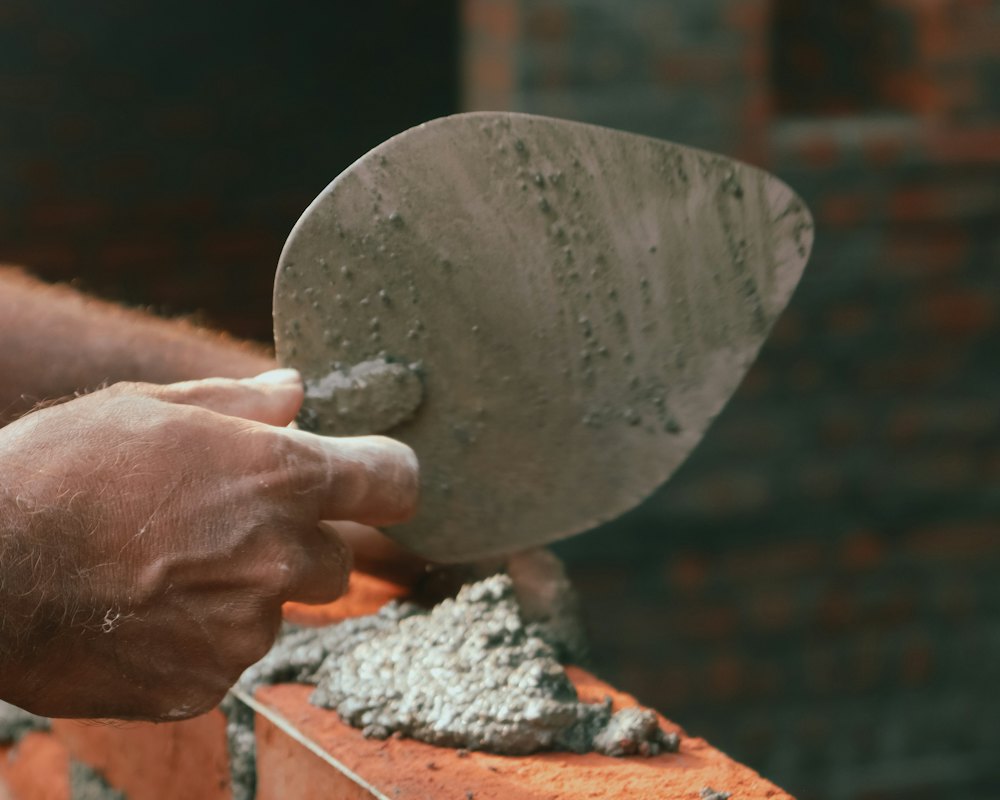 Mortar being laid on a brick wall with a trowel (stock photo)